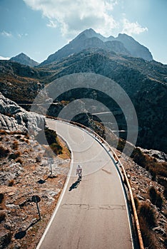 Silhouette of man on road bicycle at the top of mountains. Original sport wallpaper