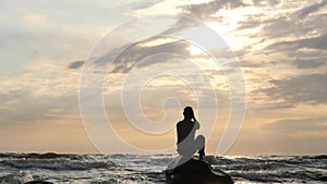 Silhouette of Man on rock in vindy sea pray to sun asking for help dolly shot