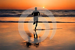 Silhouette of a man running on a beach at sunset.