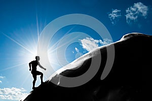 Silhouette of a man running up hill to the peak of the mountain