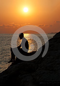 Man sitting on a rock and enjoying the sunset