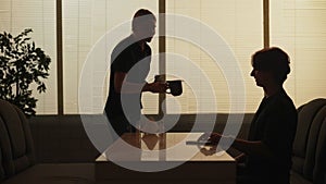 Silhouette of man sitting at the bistro bar having lunch alone, waitress brings his order cup of coffee, and dessert.