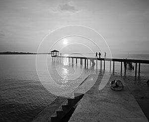 Silhouette of a man sitting on the bridge alone in black and white mode.