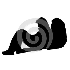 Silhouette of a man sitting on the ground with a backpack.