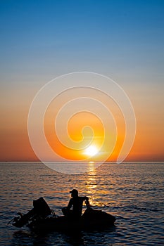Silhouette of man sitting on his jetski against sunset