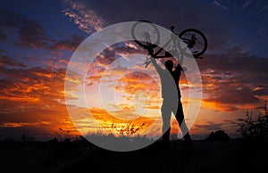 Silhouette the man stand in action lifting bicycle