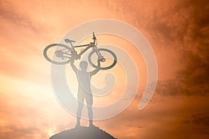 Silhouette the man stand in action lifting bicycle