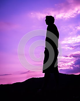 Silhouette of man standing alone on top of mountain