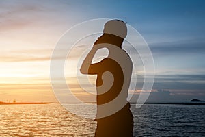 Silhouette of man standing alone on tropical beach with calm blu