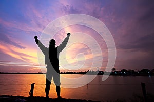 Silhouette of man standing with fists raised up on sunrise background, successful, achievement and winning concept