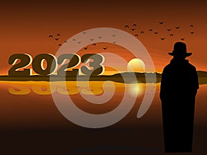 Silhouette of a man standing looking at the numbers 2023 With the sea and the sunset in  background