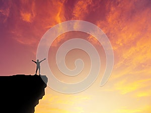 Silhouette man standing on mountain cliff sunset background