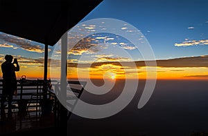 Silhouette of a man standing take a photo on the mountain