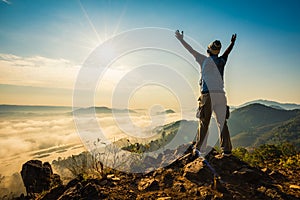 Silhouette man standing on top of the mountain watching the sun rise with fog