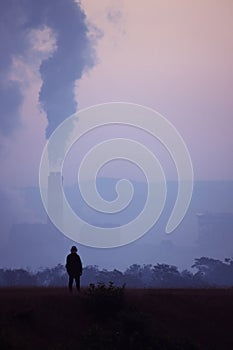 Silhouette of a man standing watching a coal power plant.