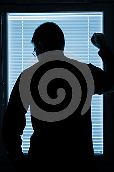 Silhouette of a man standing by the window