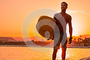 Silhouette man surfer in sunset light walking down beach with surfboard near waters edge enjoying summer time practice