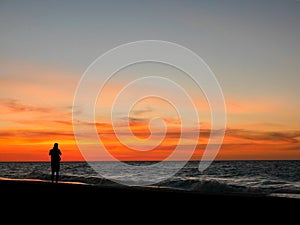 Silhouette man taking photo on sunset beach