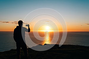 Silhouette of a man taking pictures of sunset