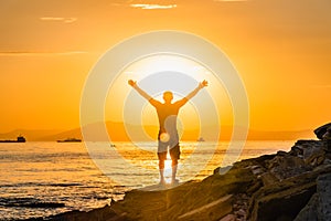 Silhouette of man with their hands in the sunset on the sea