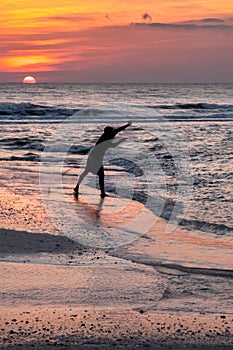 A silhouette of a man throwing a cast net for bait fish with the