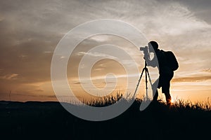 Silhouette of man with tripod taking pictures of sunset