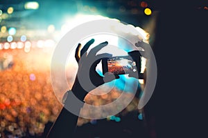 Silhouette of man using smartphone to take a video at a concert. Modern lifestyle with hipster taking pictures and videos