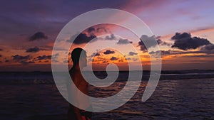 Silhouette of man walking on the beach at sunset, recreating at tropical island on vacations, relaxed lifestyle. Man