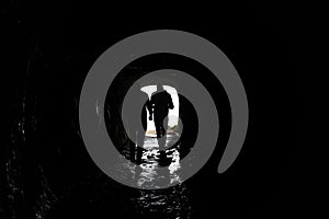 Silhouette of a man walking through a dark tunnel