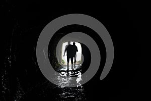 Silhouette of a man walking through a dark tunnel