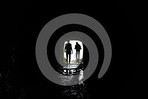 Silhouette of a man walking through a dark tunnel