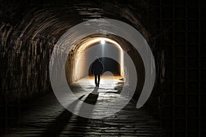 Silhouette of Man Walking at the End of Tunnel with Light