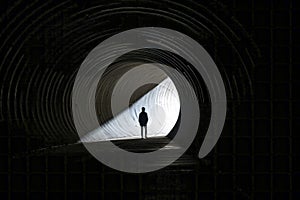 Silhouette of Man Walking at the End of Tunnel with Light