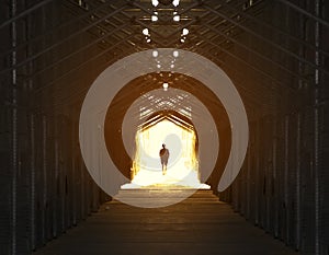 Silhouette of a man walking into light at the end of a tunnel