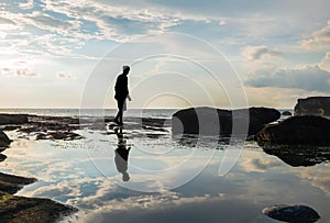 Silhouette, a man walking with reflection on water