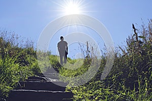 Silhouette of man walking up a stair towards the sun photo