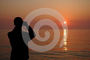 Silhouette of a man watching the sunset with binoculars