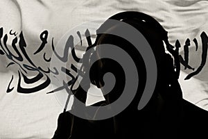 The silhouette of a man wearing headphones against the background of the Taliban flag, an eavesdropping secret agent, spy and inte