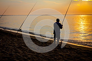 Silhouette of man who is fishing on the beach in sunrise morning