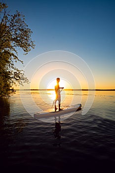 Silhouette of man who is paddling on a SUP board
