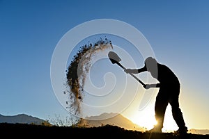 Silhouette of a man who the soil with a shovel