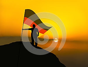 Silhouette man winner waving germany flag on top of the mountain peak