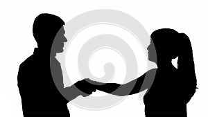 Silhouette of a man and woman greeting each other by the hand