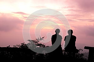 Silhouette Man and woman sitting watch the evening sky at purple sunset photo