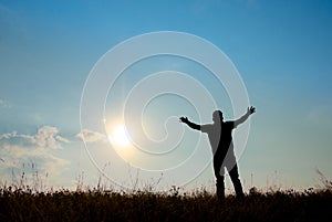 Silhouette of man worship with hands raised to the sky in nature