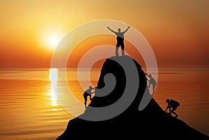 Silhouette of a mans on a mountain top on sunset background.