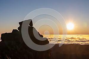 Areeiro - Silhouette of massive rock against romantic sunrise seen from mountain peak Pico do Areeiro, Madeira island photo