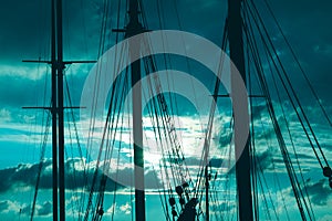 Silhouette of masts and ropes of a wooden old sailing ship against the background of the evening dark blue magical sky