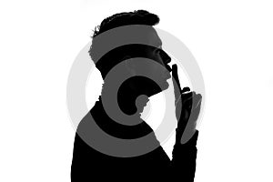 Silhouette of mature man making silence gesture standing on profile.