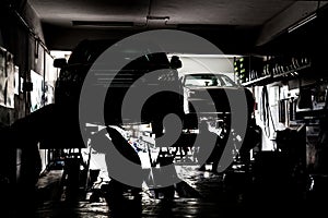 Silhouette of mechanics servicing cars at a small workshop